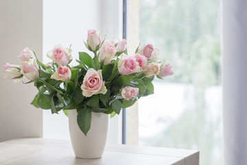 pink roses in vase on  background window