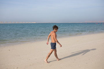 Fototapeta na wymiar Young man walking along the beach.