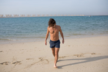 Fototapeta na wymiar Young man with curly hair on the beach.