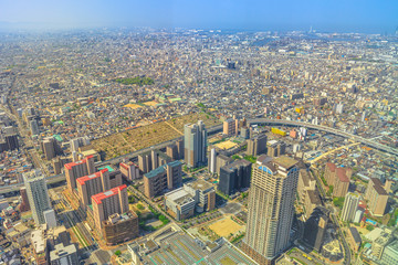 Fototapeta premium Aerial view of Osaka skyline from observation deck of viewing platform of a top of Osaka's Abeno Harukas, the tallest skyscraper in Japan. Sunny day. Osaka Bay and many bridges on background.