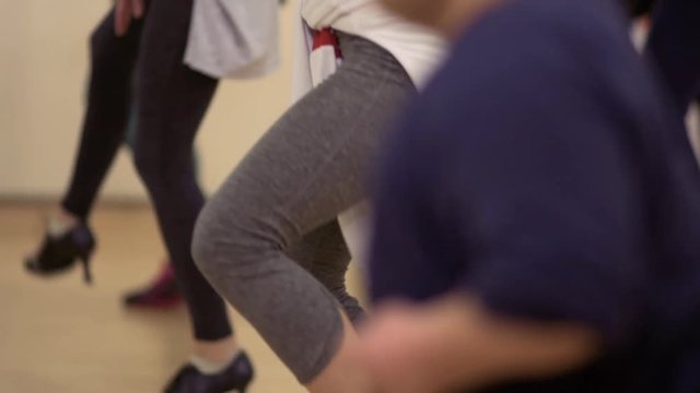 The dwarf man dances together with girls in the studio