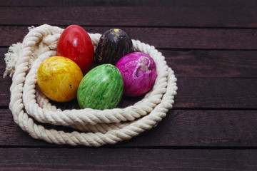 Painted Easter egg in rope on wood background