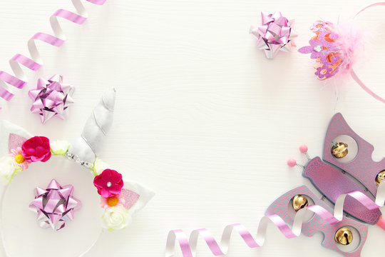 girl's party concept. unicorn head decoration, pink wand and toy over white wooden background.