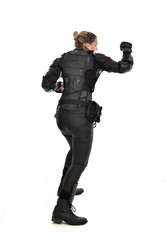 full length portrait of female  soldier wearing black  tactical armour with arms raised, isolated on white studio background.