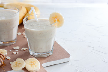 Banana smoothies with almonds and honey in a glass cup, copy space