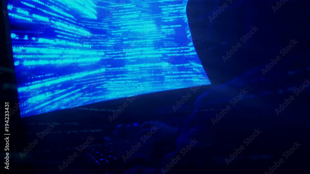 Poster a man hacker in a hood in a dark room works with the program code
