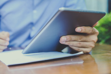 Business man working on digital tablet and writing document in street cafe. Close up