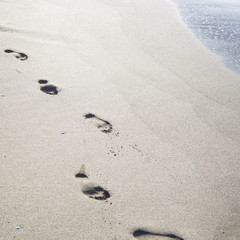Footprints in the sand by the sea. Summer beach holiday concept. Seasonal trips to the sea or the ocean. Copyspace