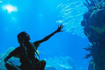 Girl watching fish through the glass in Oceanarium