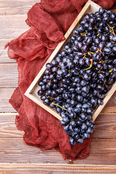Photo of black grapes in wooden box with claret cloth