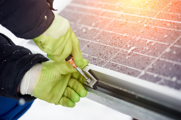 Electricity technician installing blue solar panels with screw. Photovoltaic modules as renewable...