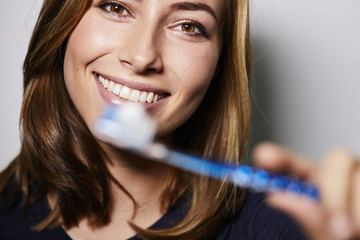 Beautiful brunette with toothbrush to camera, portrait