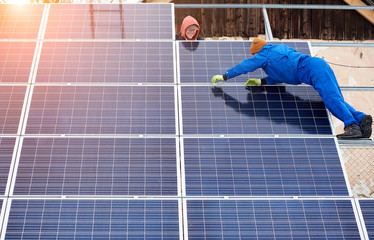 Team work. Group of professionals mounting photovoltaic solar modules on roof top during winter...