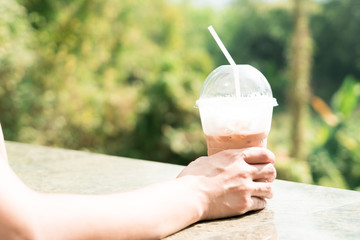 a ice coffee latte on the moring sunshine with green tree backgrounds