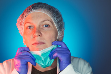 Female surgeon takes off protective surgical mask after operation
