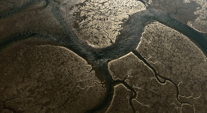 aerial image taken on a cold winter day of the Bay Bassin d'Arcachon at low tide, revealing a miraculous golden reflection on the sand