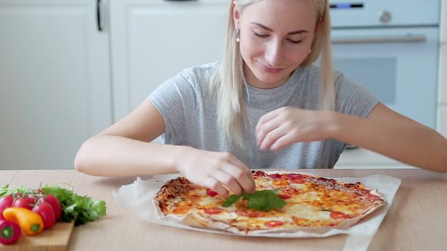 cooked pizza Margarita on the table, woman puts Basil on pizza