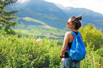 woman tourist with a backpack and glasses travels and stands on the background of a mountain a beautiful natural landscape