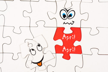 Puzzle pieces with tow funny faces and the words april, april