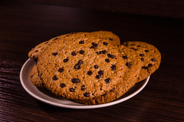 Plate with chocolate chip cookies on a dark wooden table