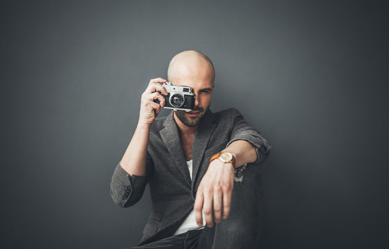 A bald man taking photos indoors enjoying