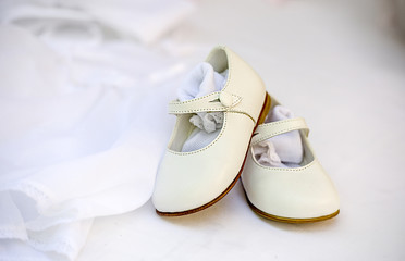 Small baby girl shoes on lace dress as background