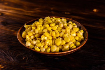 Ceramic plate with canned corn seeds on wooden table