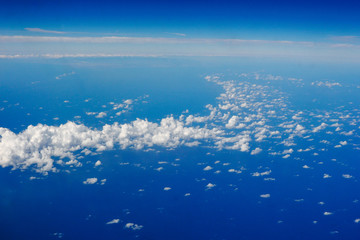 Fototapeta na wymiar Blue sky and clouds below from airplane window
