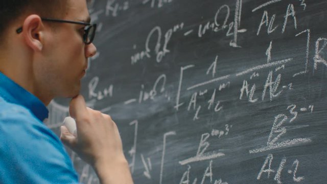 Brilliant Young Mathematician Writes Math Equation/ Formula on the Blackboard. 