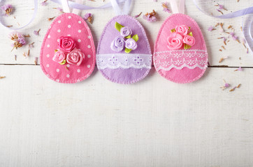 Handmade patchwork pink and lilac felt easter eggs on white wooden table - obrazy, fototapety, plakaty