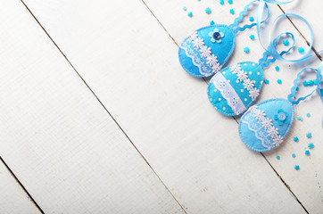 Handmade patchwork blue felt easter eggs on white wooden table