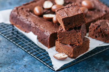 Dark chocolate brownie square on a wire rack decorated with creamy chocolate eggs. Blue stone...