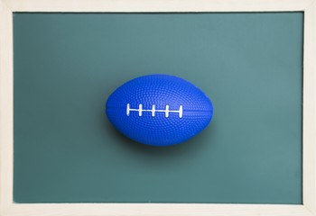 Rugby shape hand massage ball over blurred blackboard, Blue rugby ball hand relaxing 