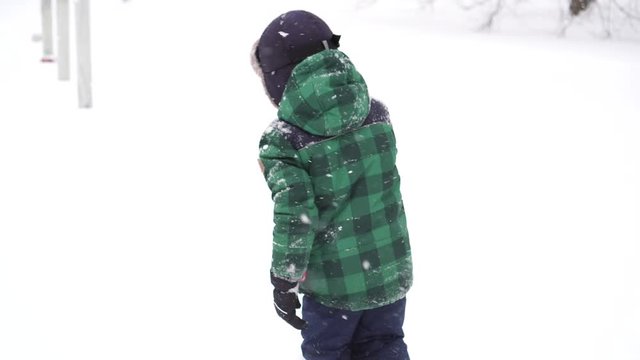 Beautiful Joyful preschooler boy having fun with snow. Winter wonderland