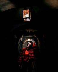 Model in red fur jacket poses under the lantern in the dark tunnel