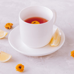 A cup of flower tea with lemon on a white stone background. Still life.