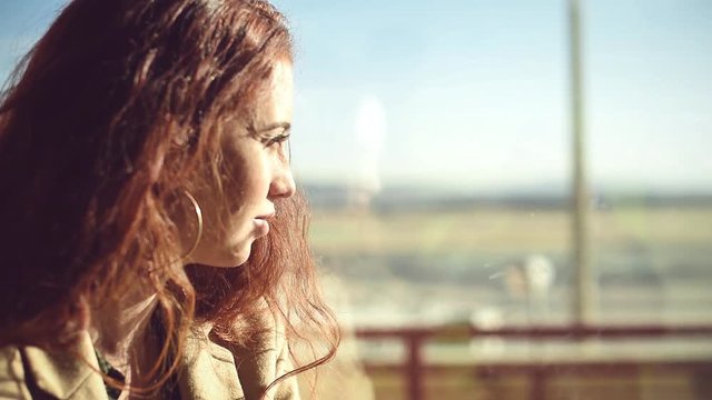 Beautiful pensive woman looking in window at the airport