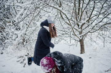 Two funny girls friends having fun at winter snowy day near snow covered trees.