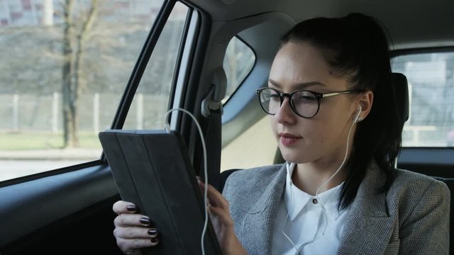 Young Businesswoman Using a Tablet in the Moving Car