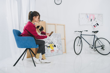 Pretty lady using tablet and hugging pug dog at home