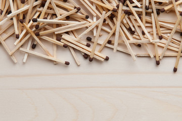 wooden unburned matches with black heads scattered against a light brown wood. empty space from below