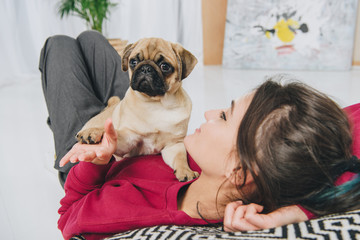 Young woman playing with pug puppy