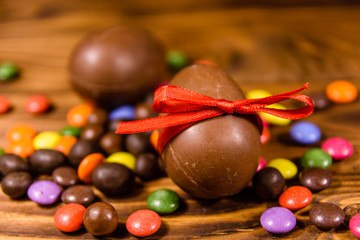 Chocolate easter eggs and multicolored candies on wooden table
