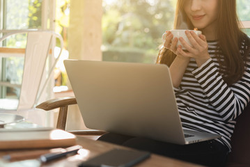 Beautiful young teenage woman freelance work with laptop have coffee at coffee shop in with sun light, freelance lifestyle conceptual