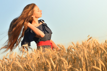 A young girl waving her long hair in the wheat field