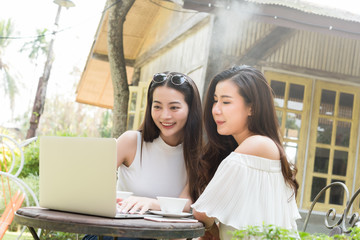 Two teenage women meet in coffee shop use laptop together in afternoon, life style of new teenager