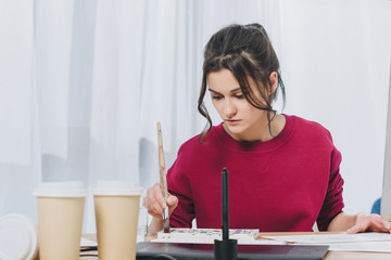 Attractive young girl working on illustrations in home office