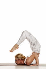 Yoga, sport, training and lifestyle concept - Young blonde woman doing yoga exercise. Portrait of young beautiful woman in white sportswear doing yoga practice.Chin stand/ Ganda bherudasana