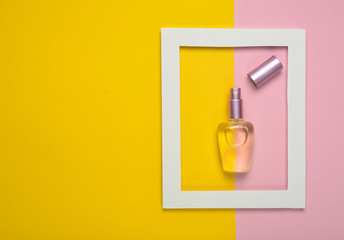 A perfume bottle in a white frame on a colored pastel background. Minimalist trend. Top view..