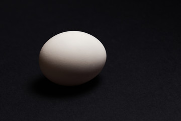 White egg on a black background, close-up.